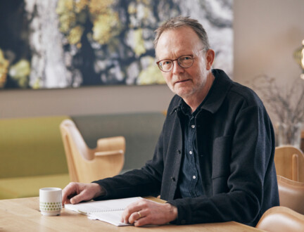 Hospicepræst Ole Raakjær sidder ved et bord med papirer foran sig.