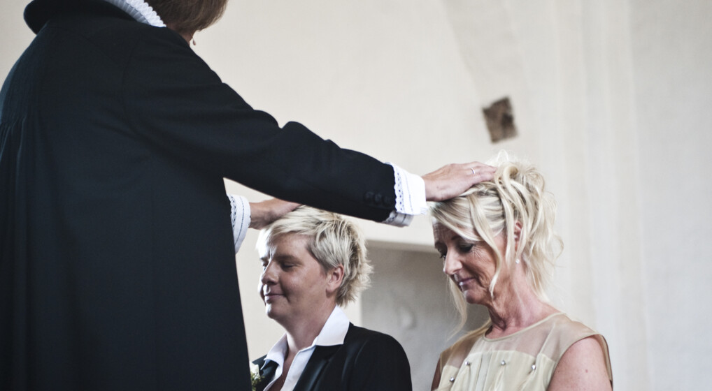 Et lesbisk par bliver velsignet af en præst til deres vielse i en kirke
