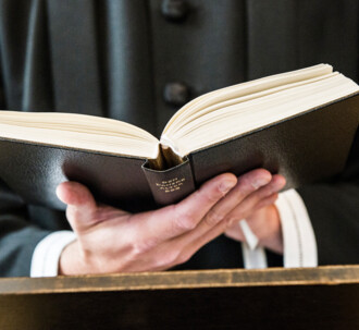 En præst kigger i den danske salmebog.