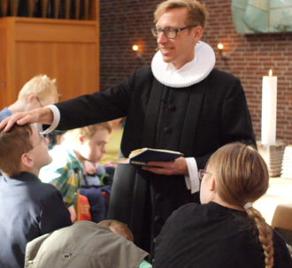 En præst konfirmerer konfirmander med særlige behov.