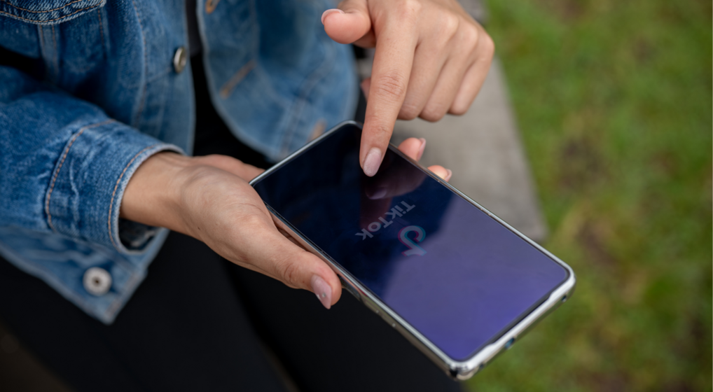 Hænder der holder en telefon med TikTok på skærmen