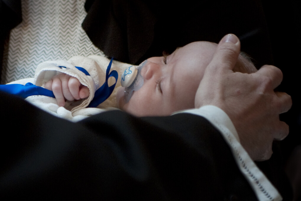 Præst lægger hånd på sovende dåbsbarns hoved