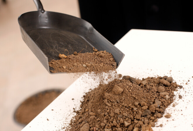 En præst kaster jord på en hvid kiste ved en bisættelse.