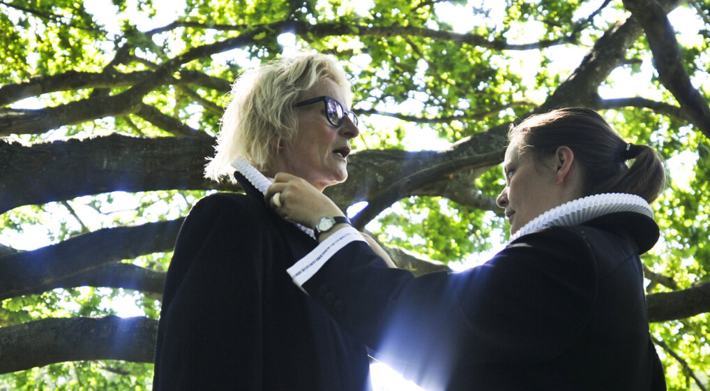 En kvindelig præst hjælper en anden kvindelig præst med at rette dennes pibekrave