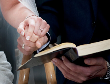 Brudepar i kirken holder i hånd og deler en salmebog